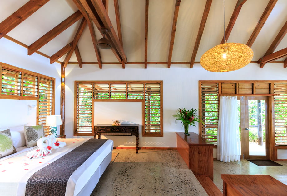 Villa bedroom with timber beams and tropical garden views