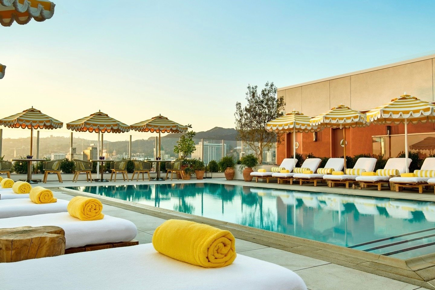 Rooftop pool surrounded by loungers and yellow-and-white umbrellas