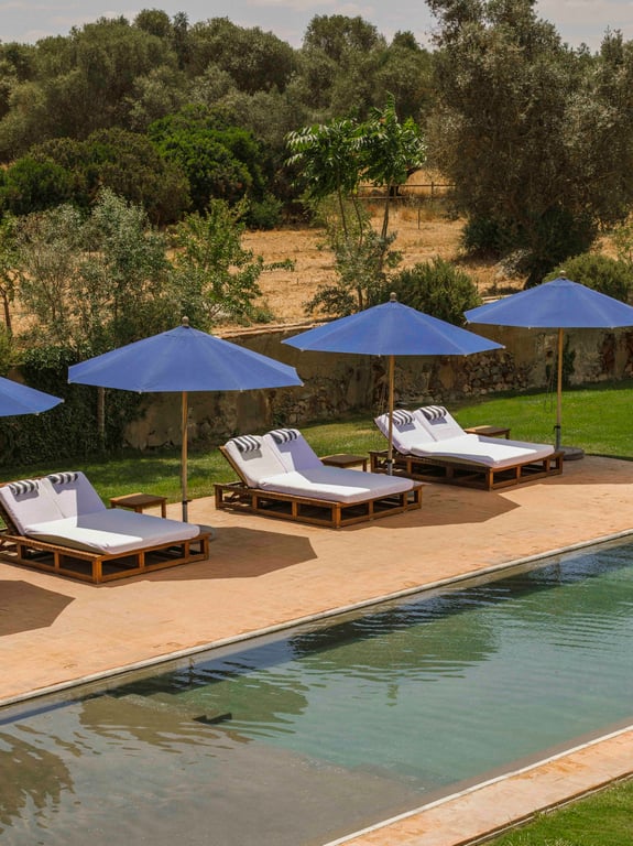 Pool loungers beneath blue umbrellas at São Lourenço do Barrocal