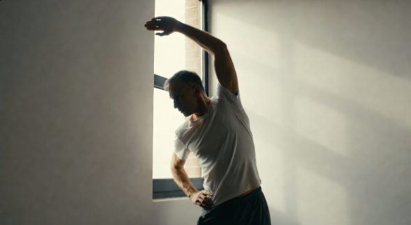 Man doing a gentle standing stretch indoors
