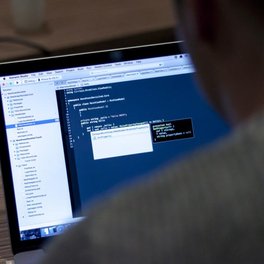 Software engineers working together at computers in an office.