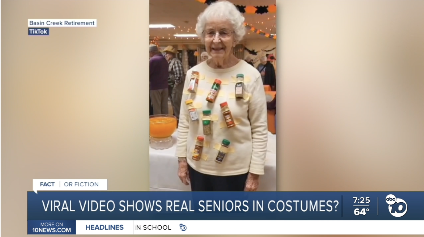 A smiling older woman in a Halloween costume made of spice jars taped to a sweater, a still from an AI-generated retirement home video