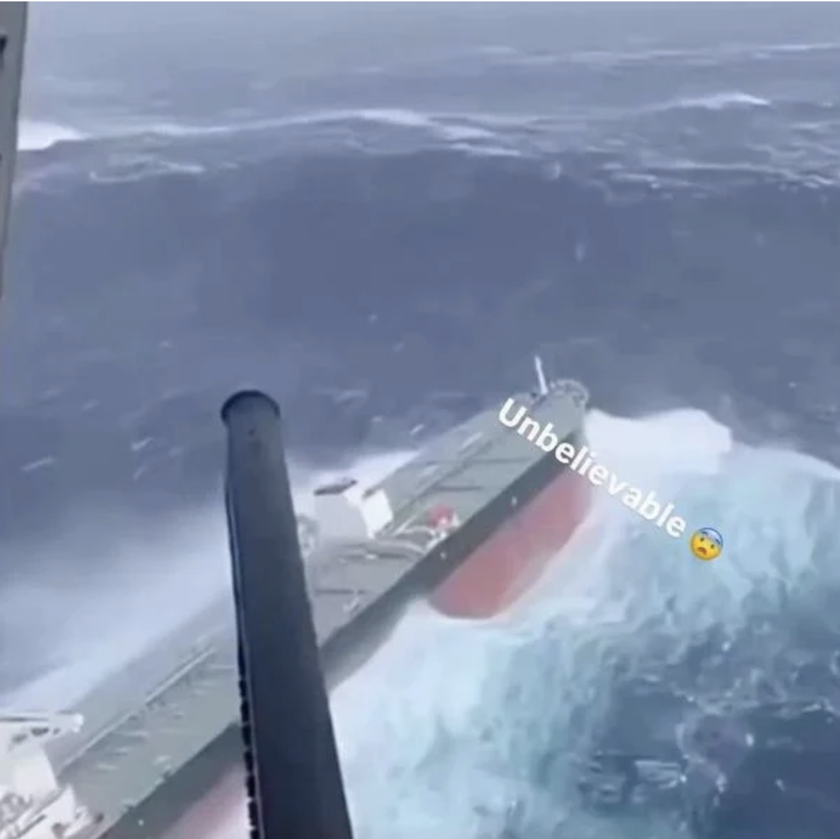 A large cargo ship being swallowed by an enormous wave crashing over its bow in a stormy ocean, a video generated with AI