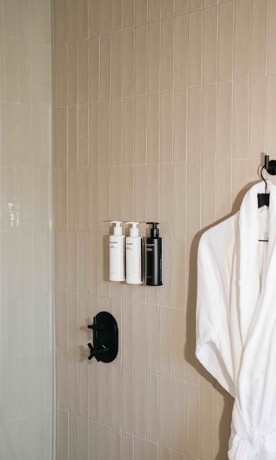 Guest shower with wall-mounted bath products and a white robe