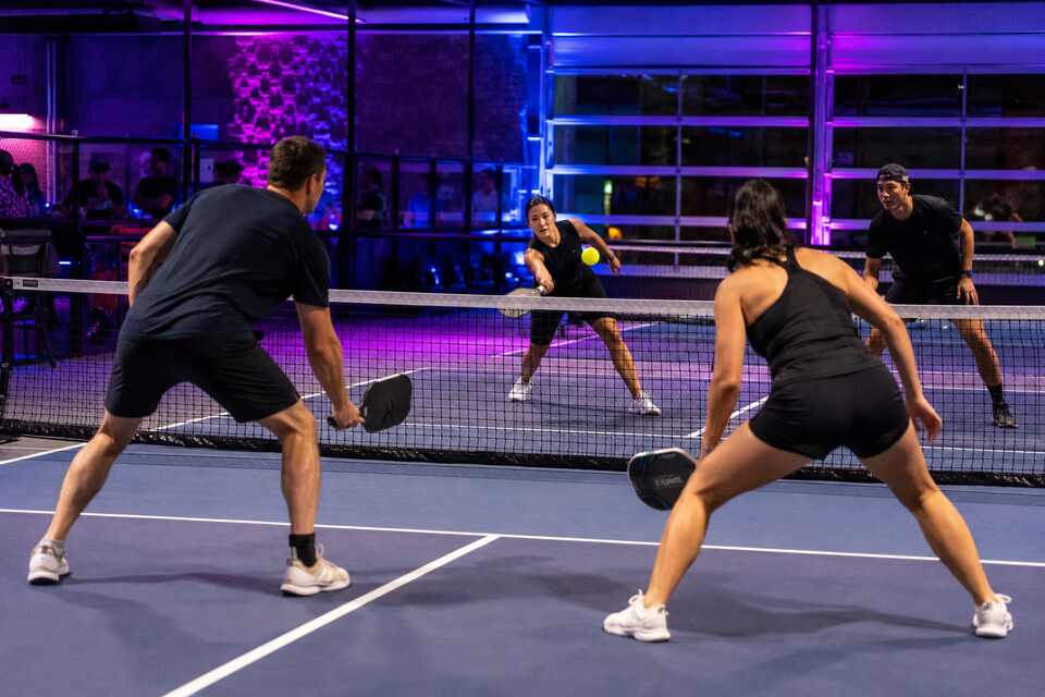 Adults playing cosmic pickleball under neon lights in Richmond BC