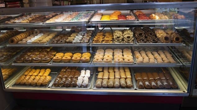 A lit bakery display case filled with trays of doughnuts and pastries