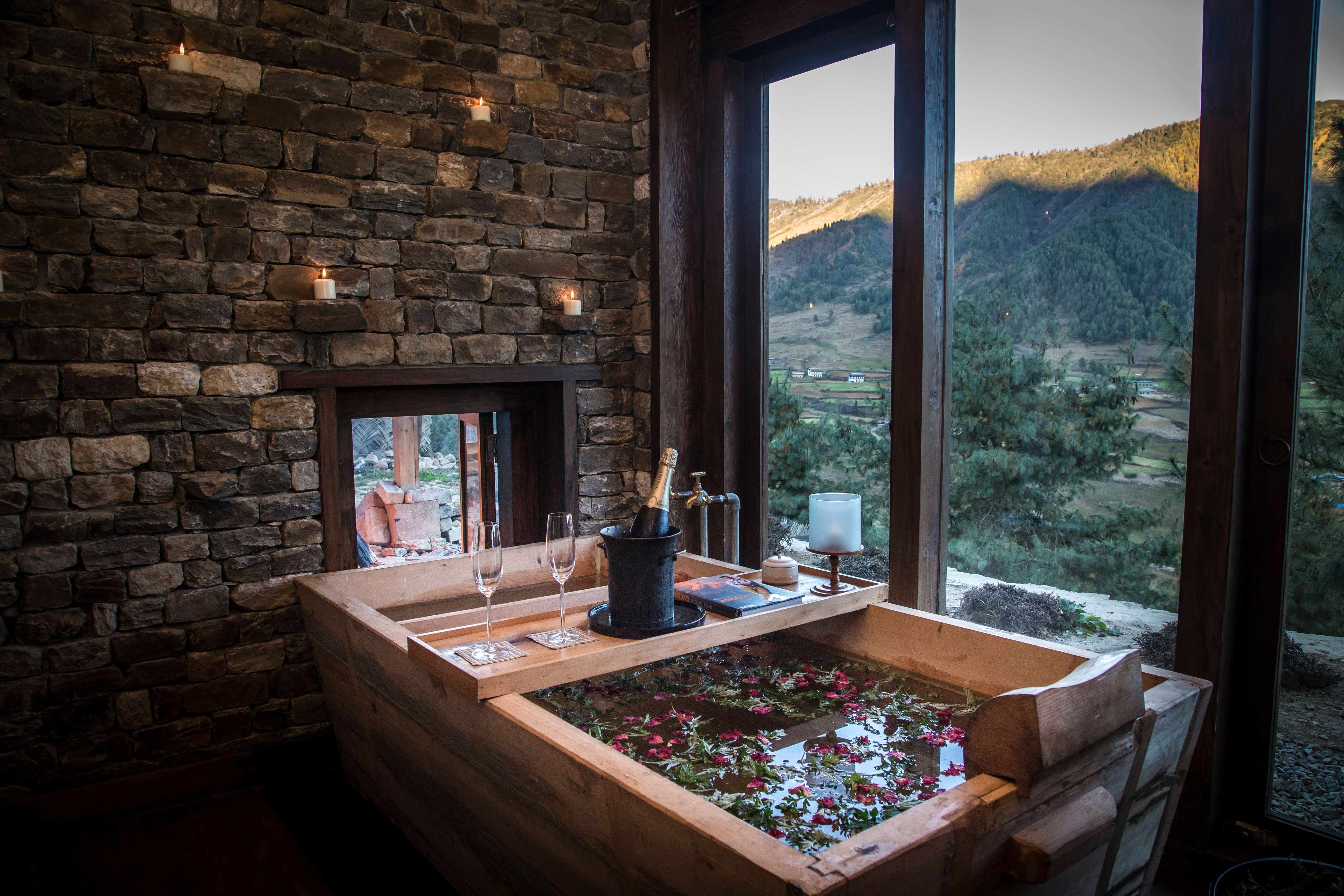 Wooden bath filled with petals beside a valley-facing window at Gangtey Lodge