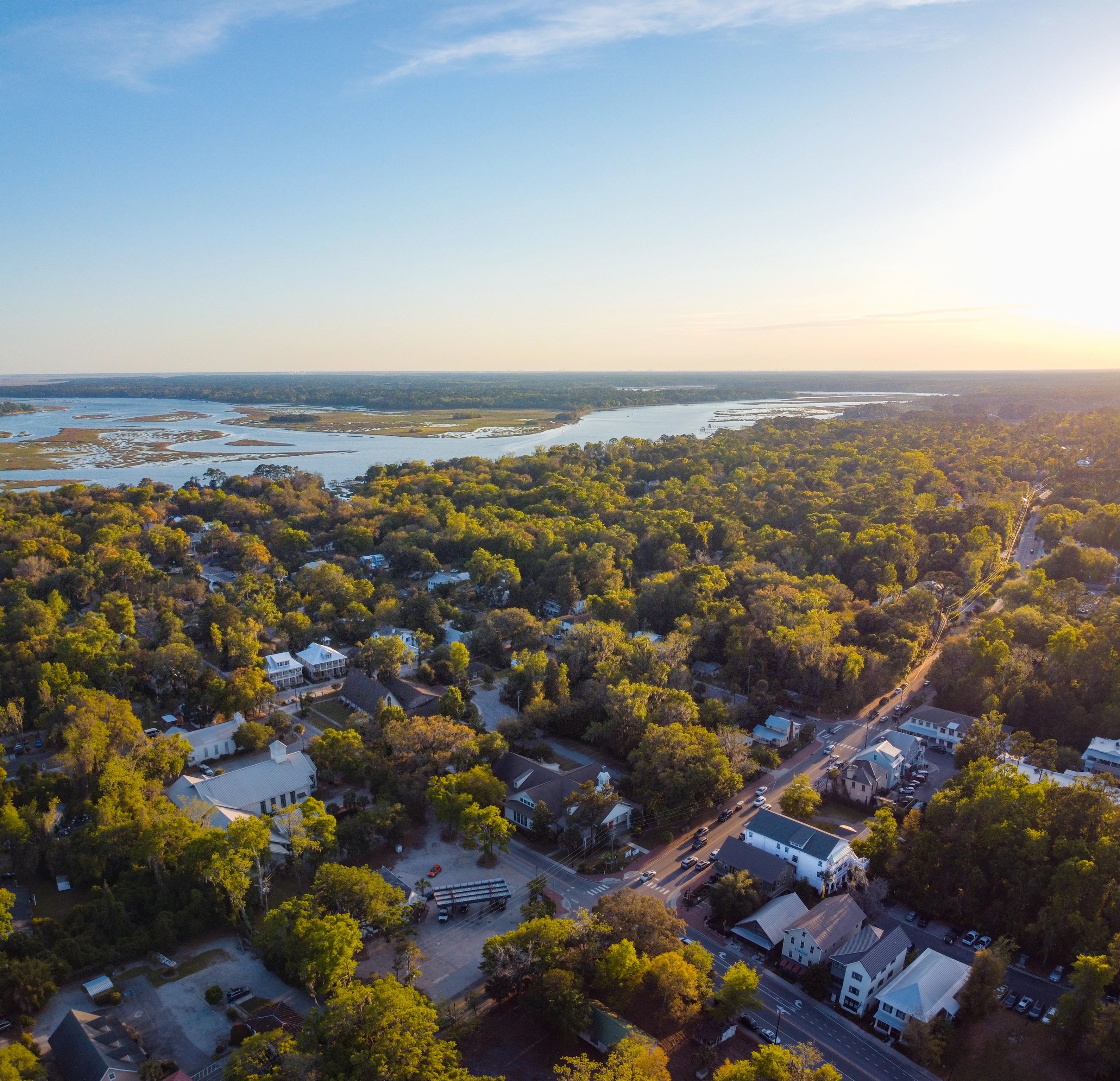 Aerial view of tree-lined Bluffton streets and the river beyond