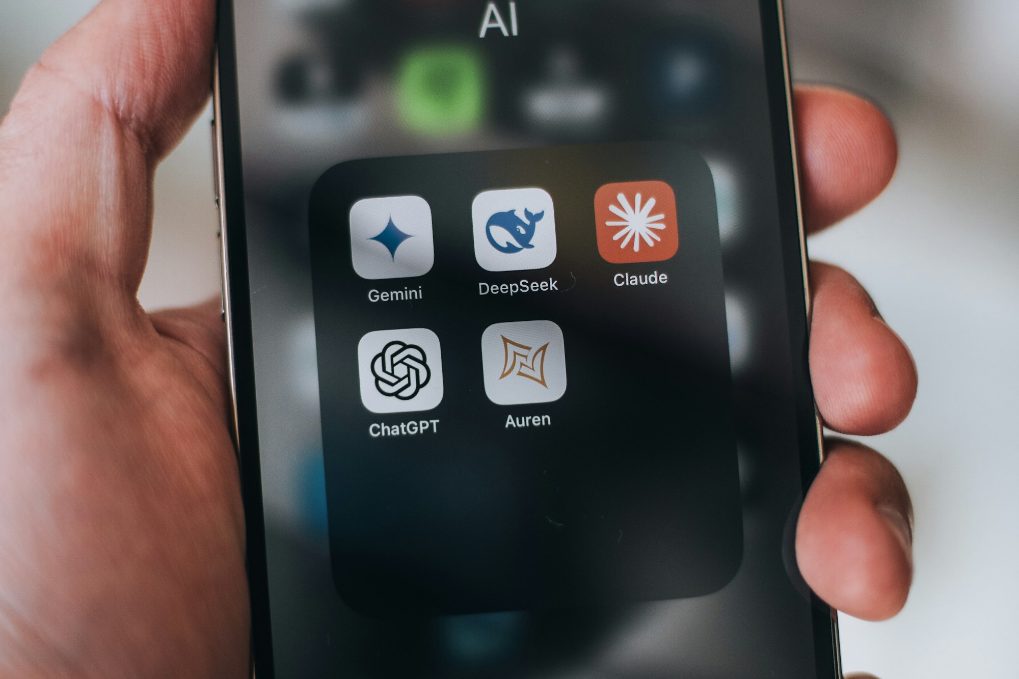 Hand holding a phone with AI application icons