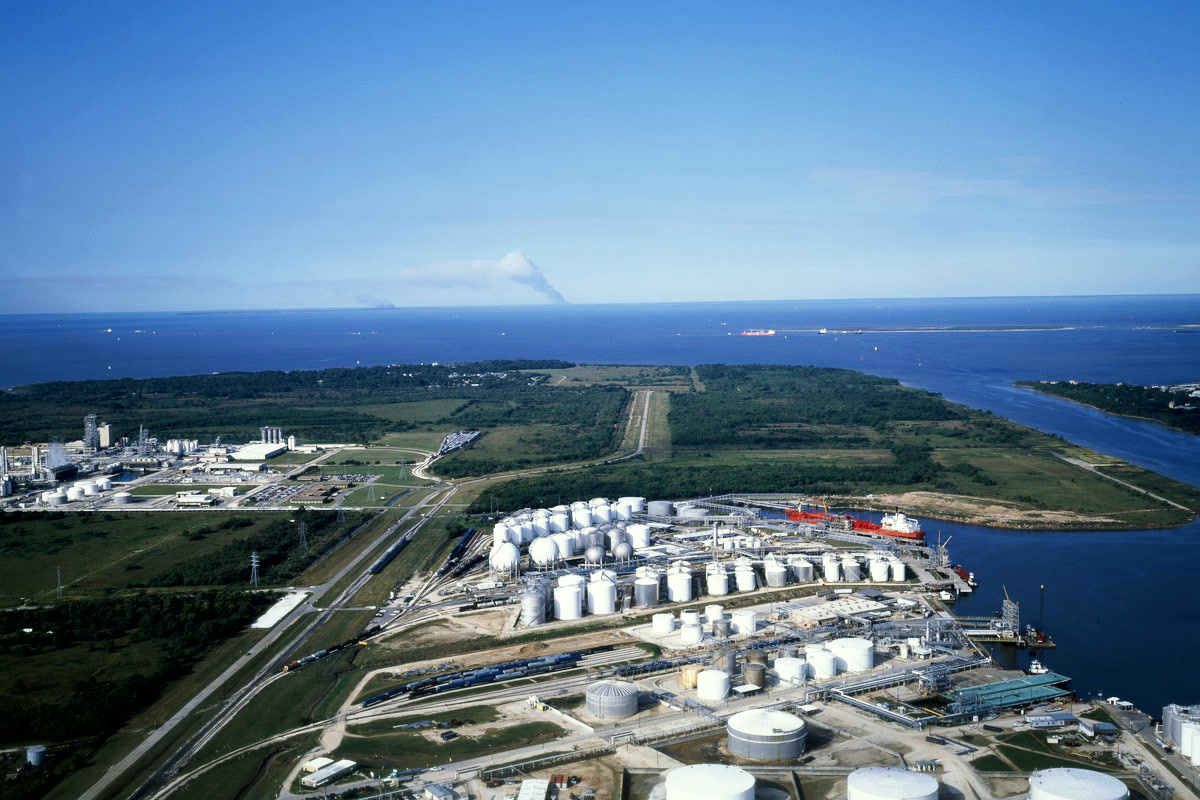 Rows of white refinery storage tanks beside a road near Houston, Texas, under a pale sky.