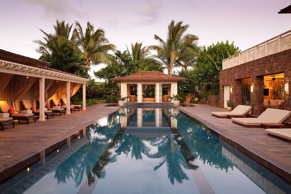 Long outdoor pool surrounded by palms and loungers