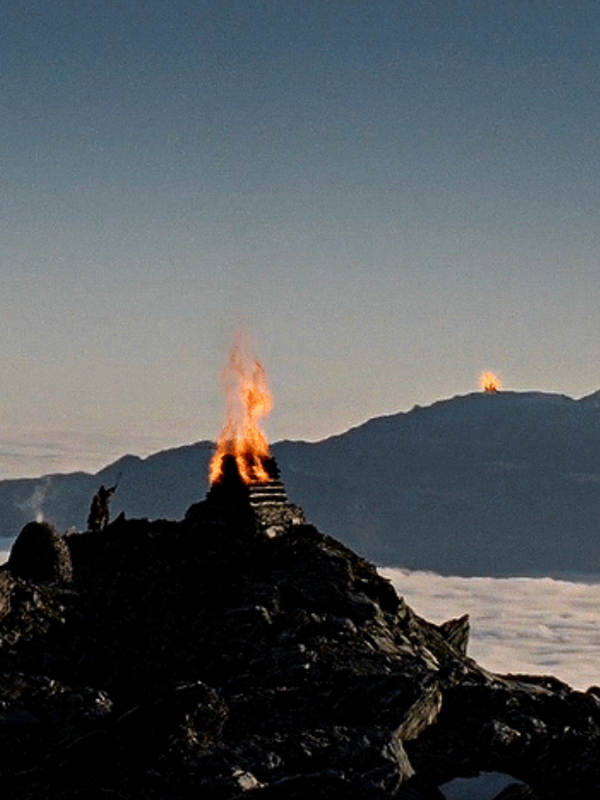 Signal fires lit on a mountaintop at dusk