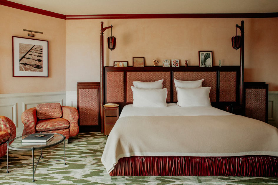 Guest room with green patterned carpet and warm wood furnishings