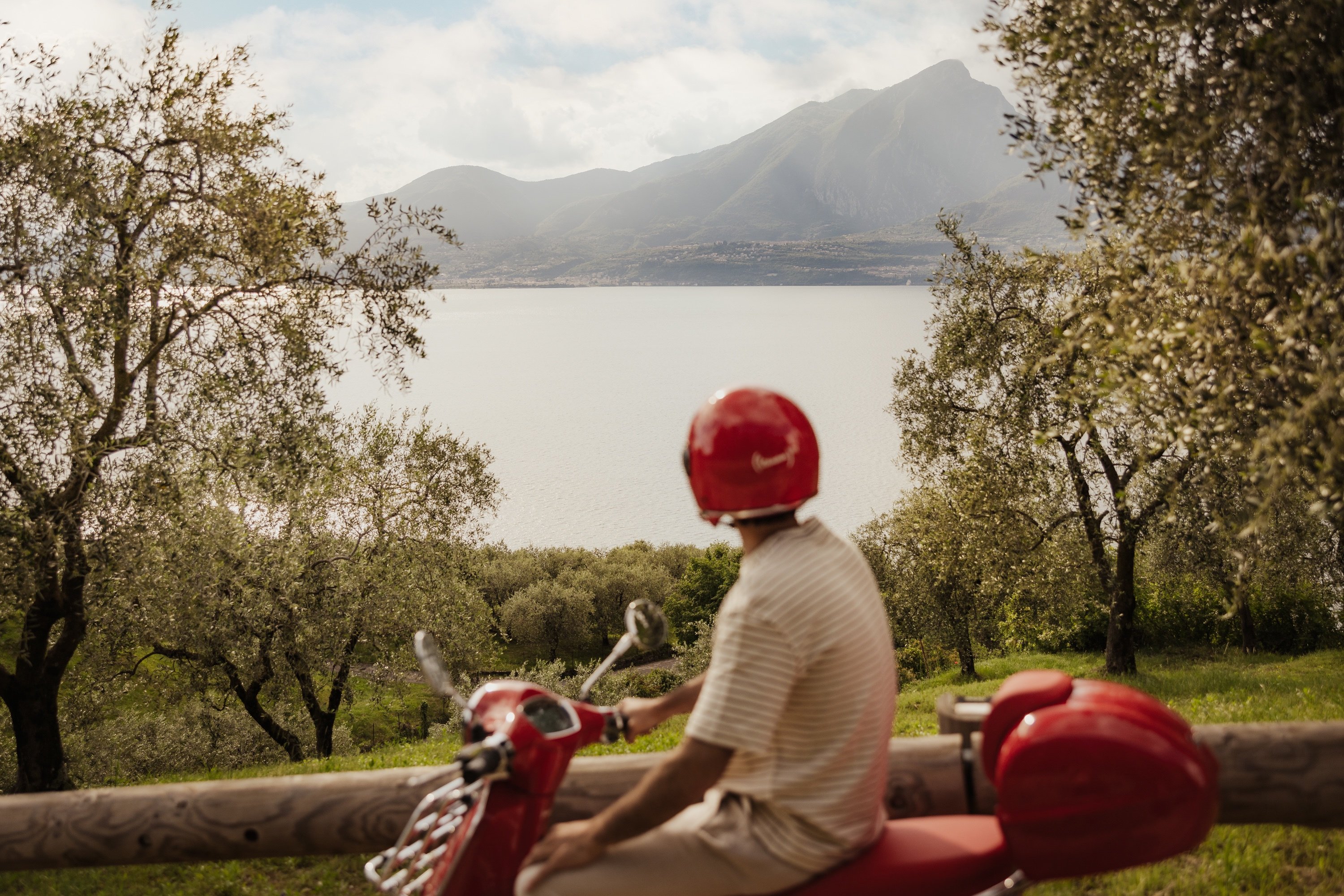 Red Vespa and matching helmet beside Lake Garda