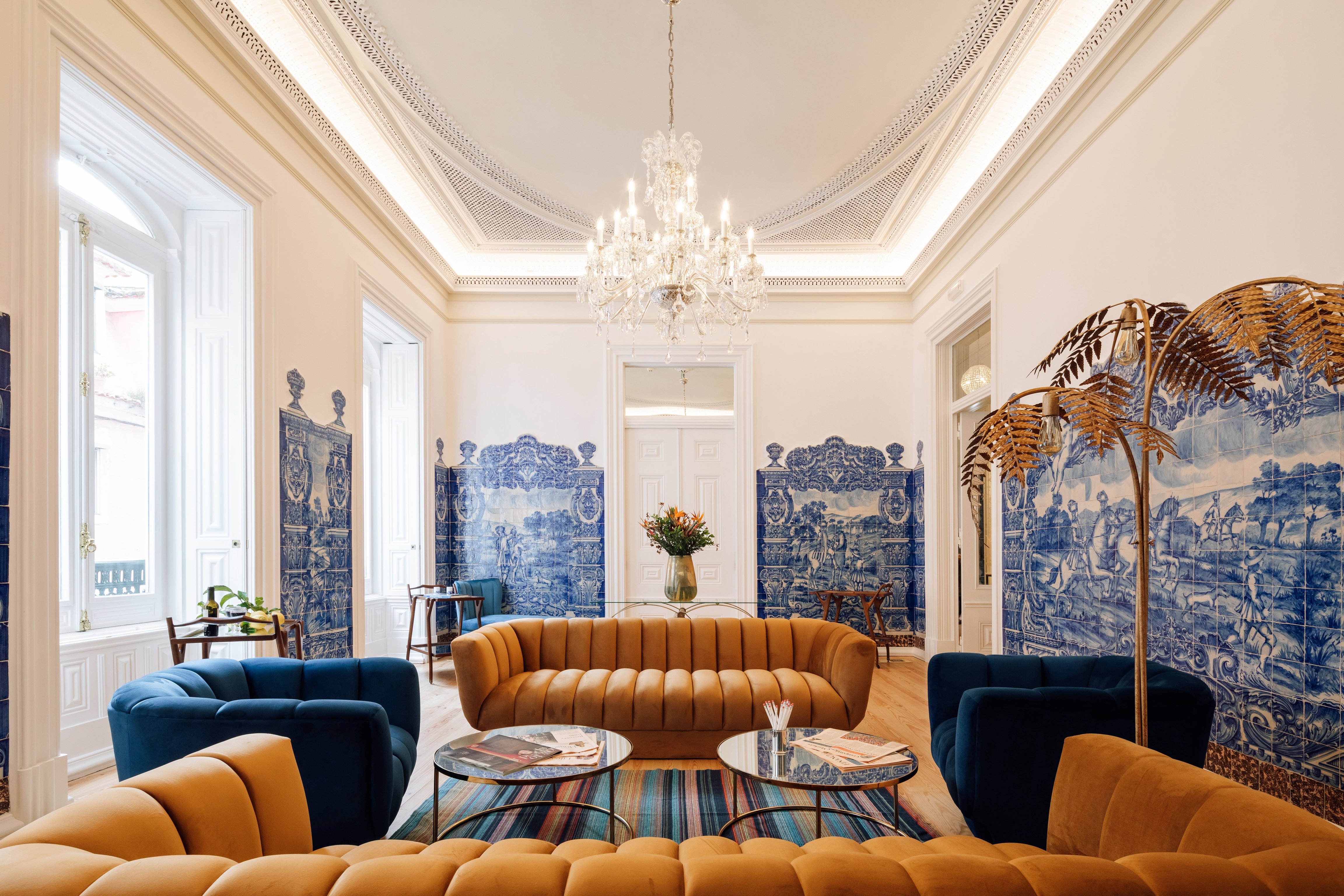 Grand Palácio Príncipe Real salon with chandelier, ochre seating, and blue decorative screens
