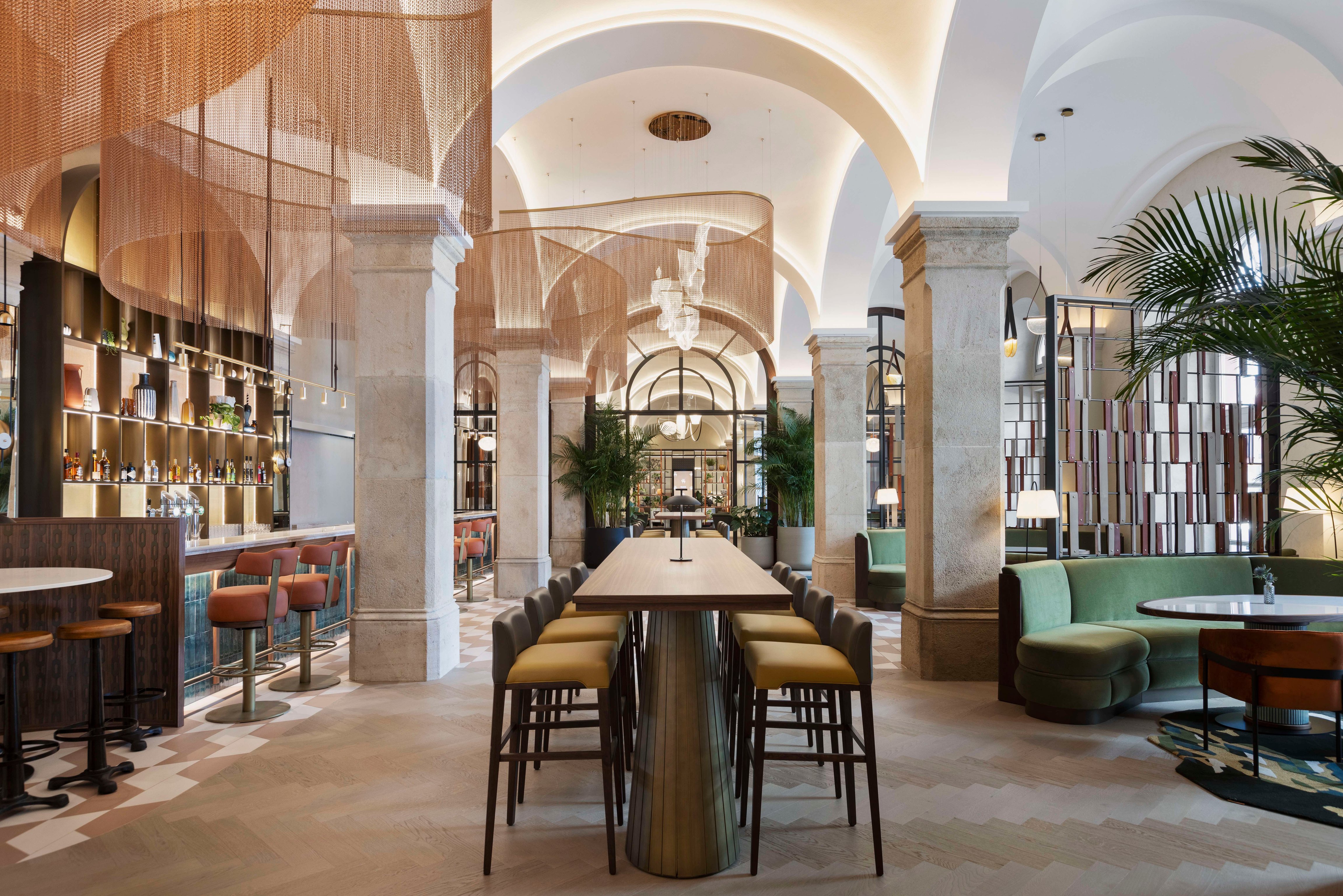 Vaulted lounge and bar with warm wood and green seating at the Imperial Riding School
