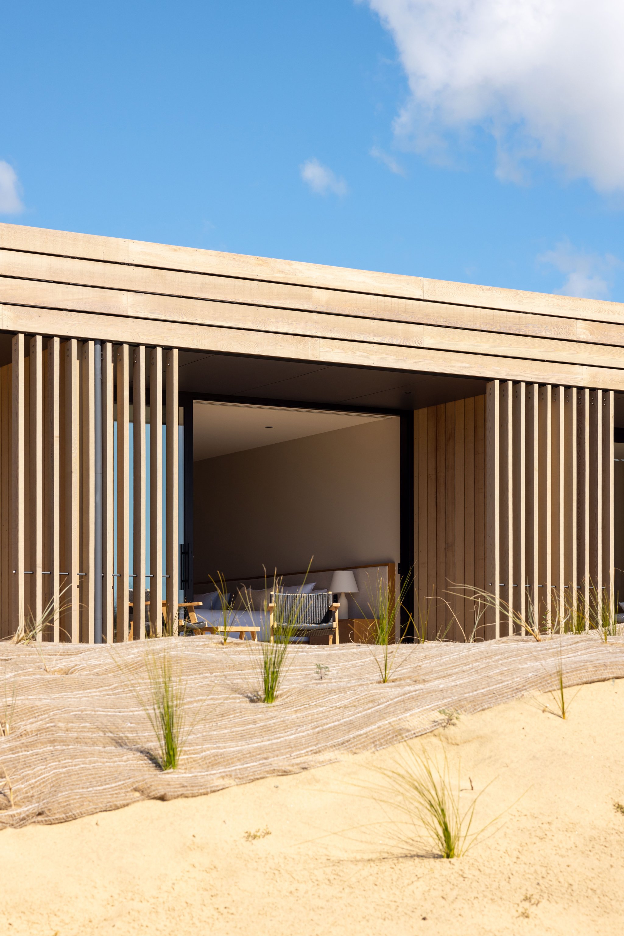 Low timber building surrounded by sand and young coastal grasses