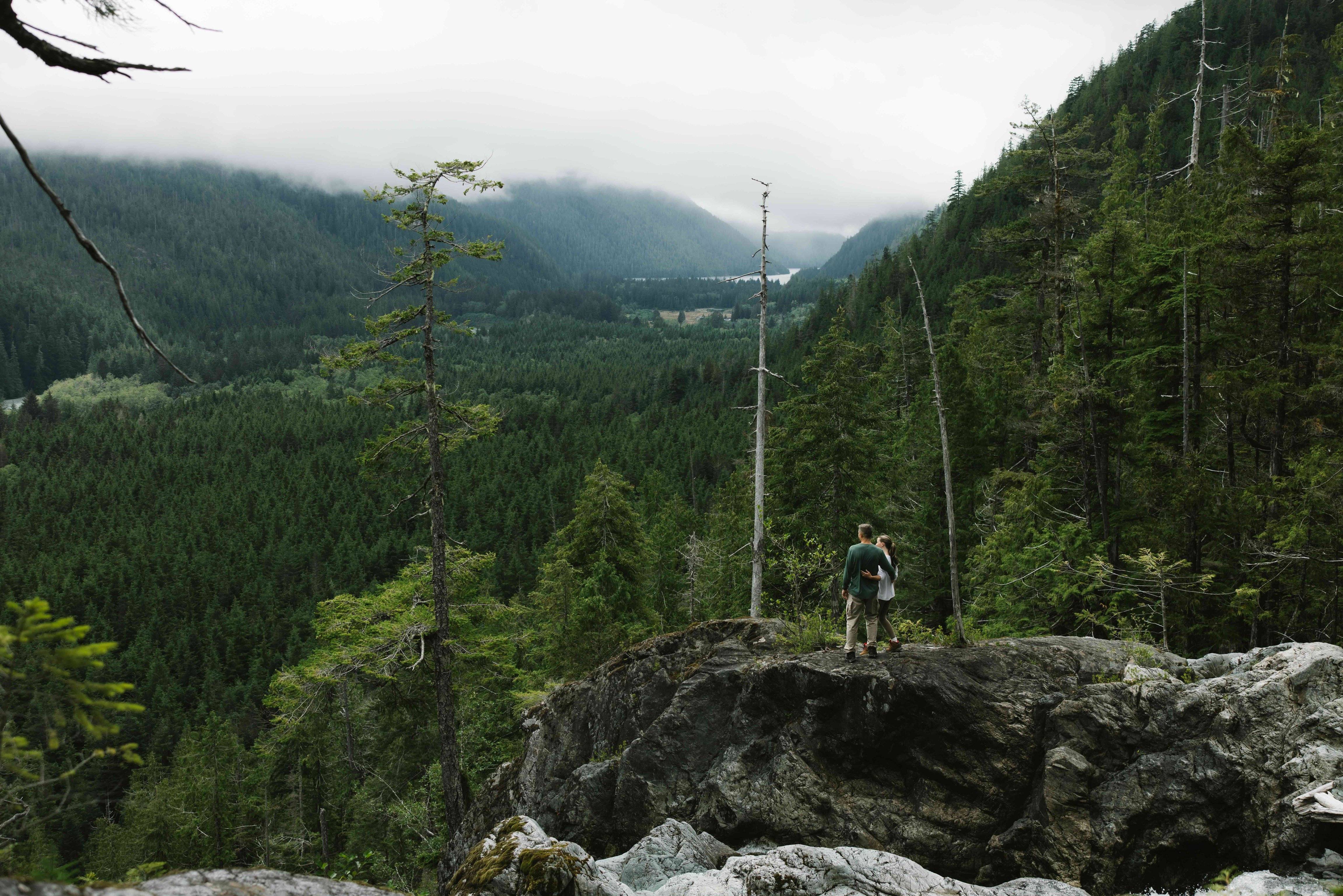 Guide and guest hiking on a rocky overlook above the coastal forest
