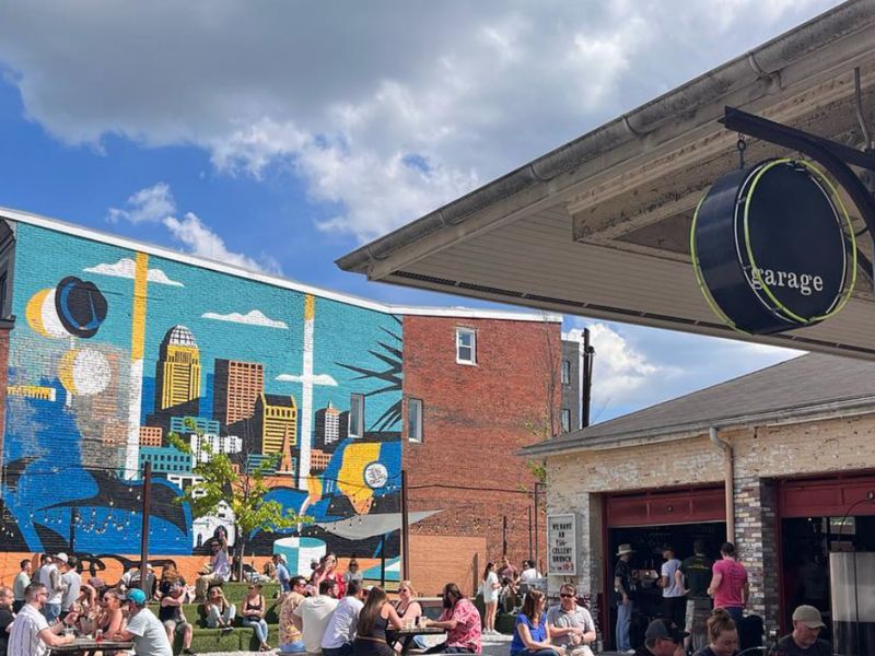 Busy lawn and picnic tables outside Garage Bar beside a city mural