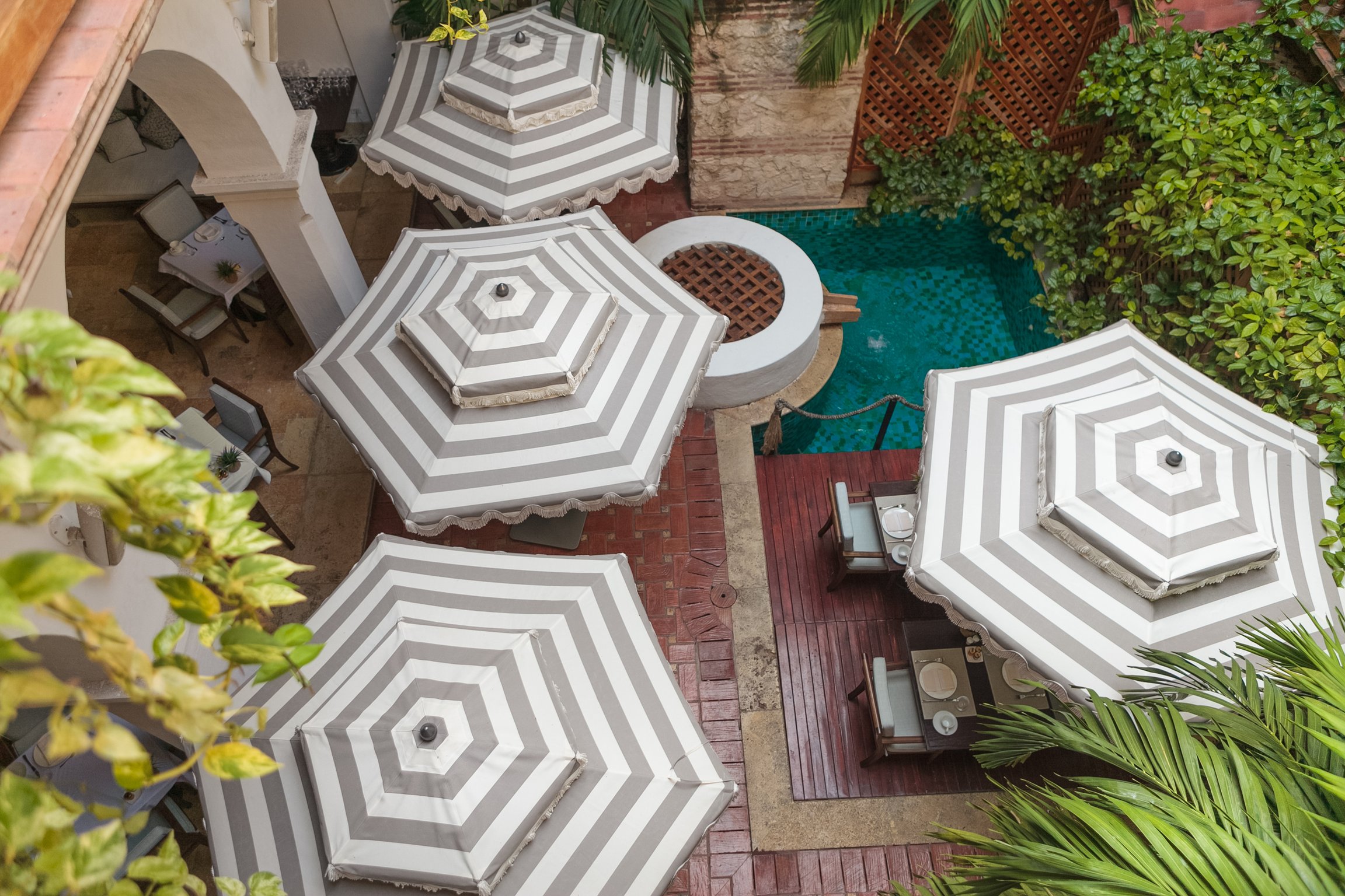Striped umbrellas and the courtyard pool at Casa San Agustín
