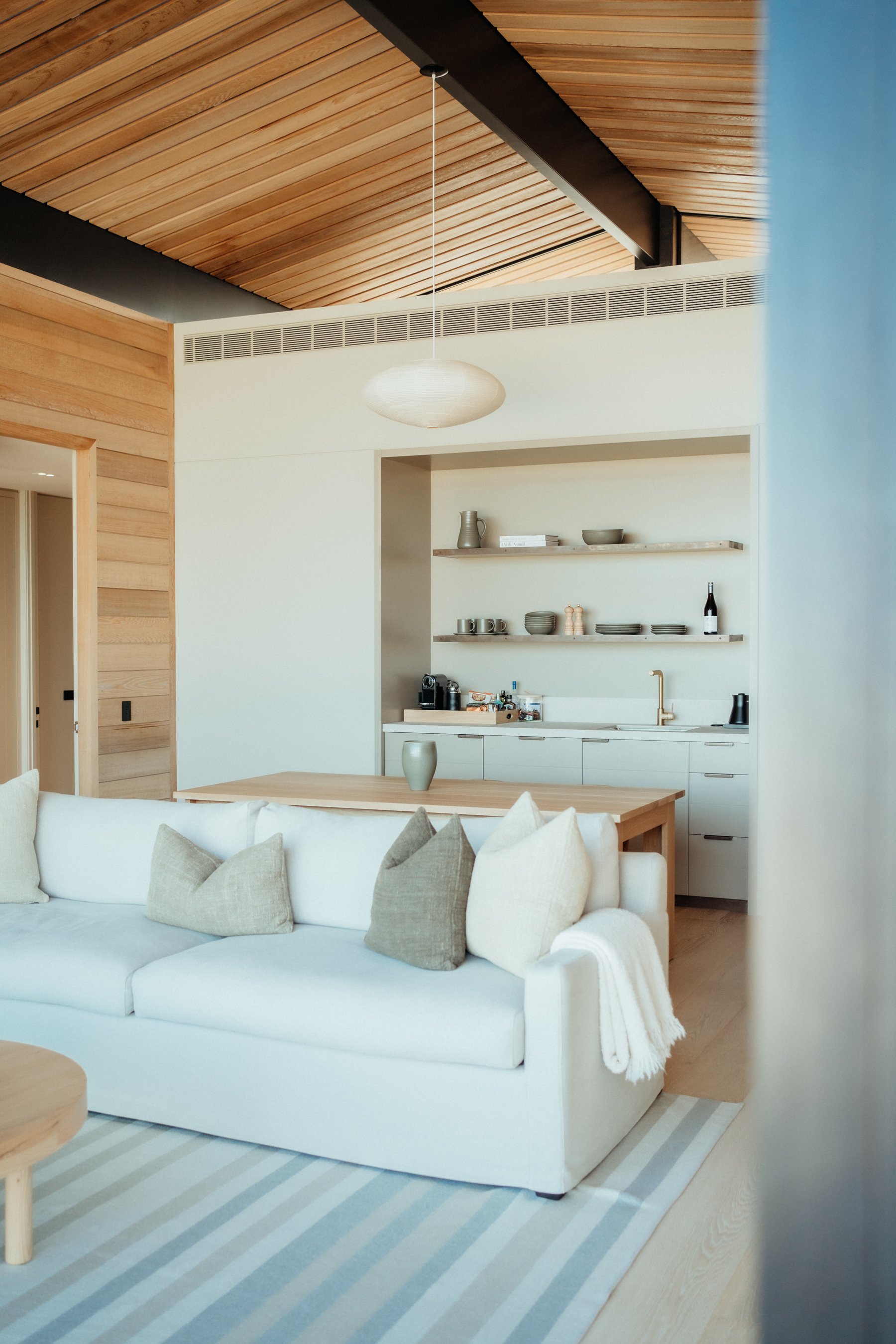 Light-filled living area with a white sofa and natural wood ceiling
