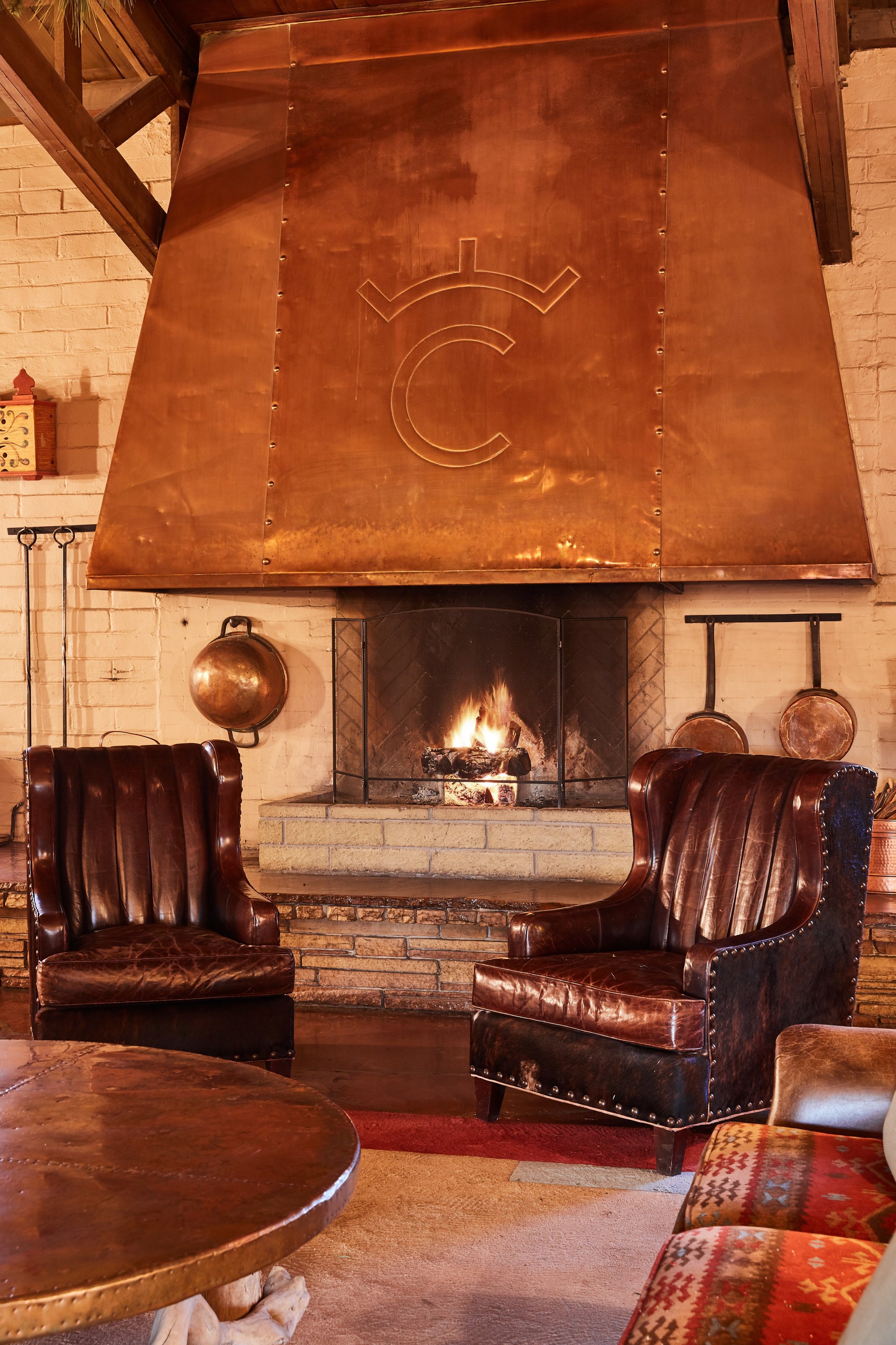 Leather armchairs beside a copper fireplace at Rancho de los Caballeros
