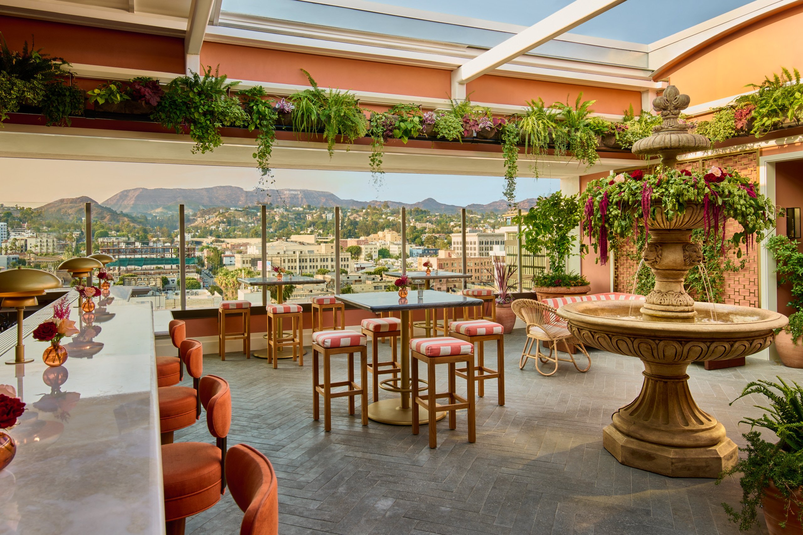 Open-air rooftop bar with a fountain, plants, and views of the Hollywood Hills