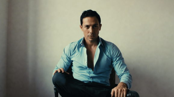 Man sitting in a chair doing a figure-four leg stretch