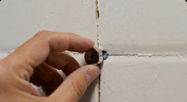 A small powerful magnet sticking to a drywall surface to find a stud