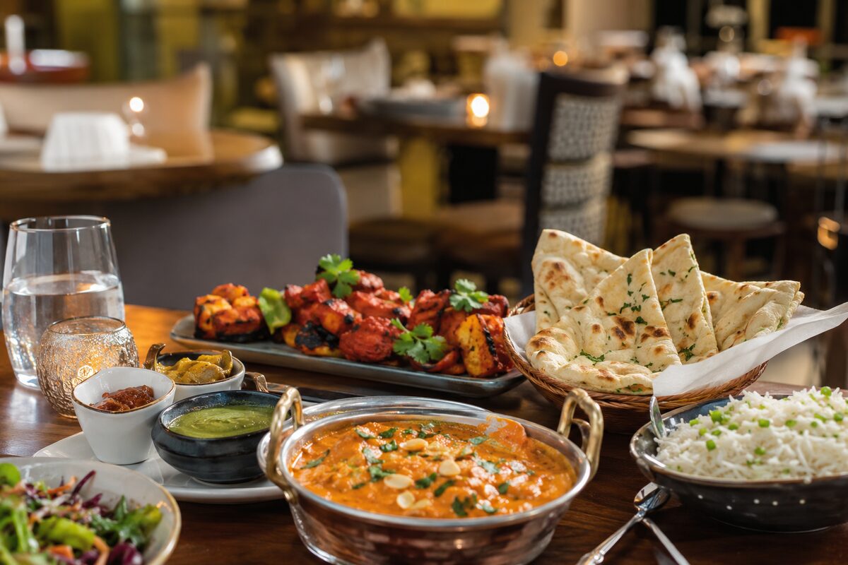 Indian curry, tandoori dishes, naan and basmati rice on a restaurant table