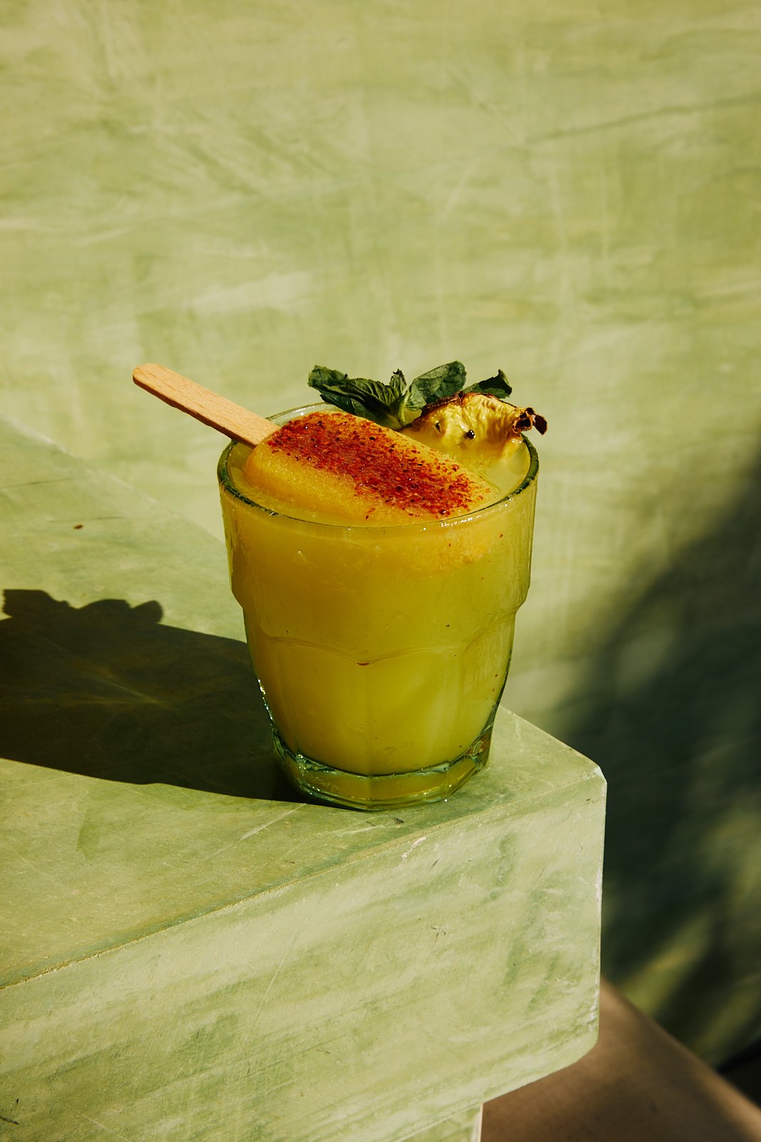 Tropical cocktail against a mint-green wall at Punta Nayaá