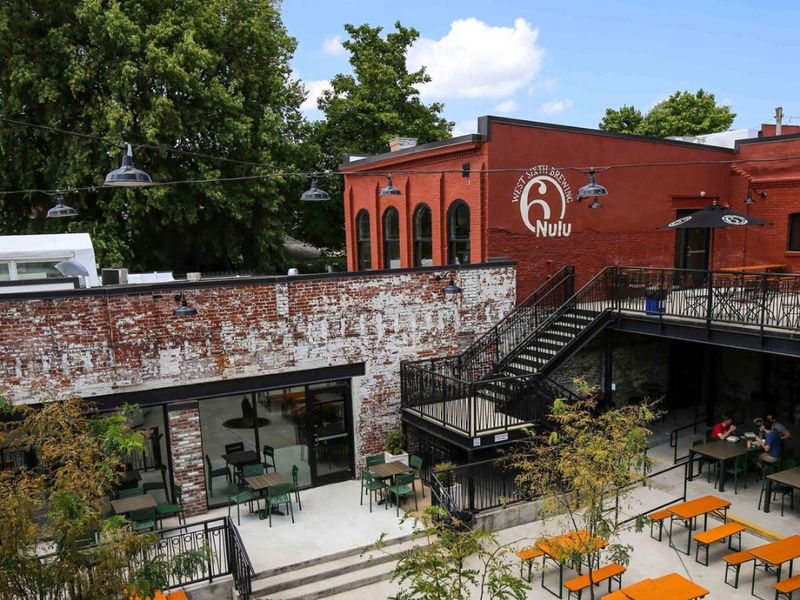 Courtyard beer garden with orange picnic tables at West Sixth NuLu
