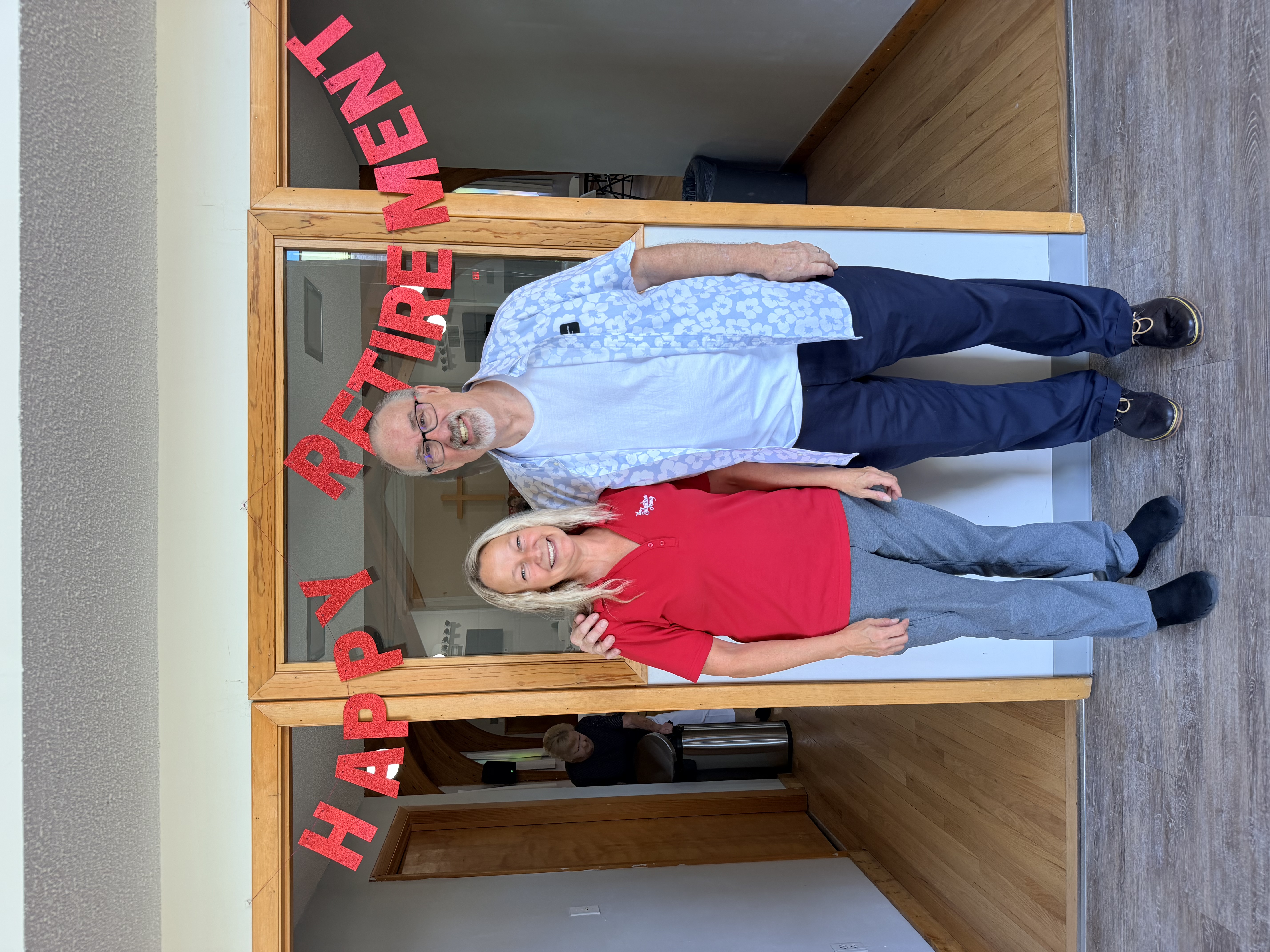 Larry Hostetler and Danette Davidson in front of Happy Retirement sign