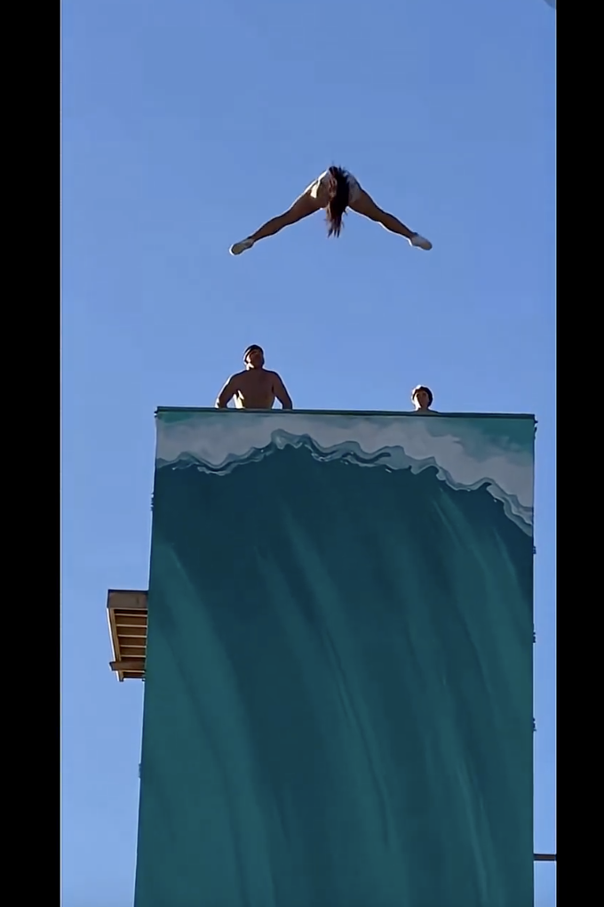 An athlete mid-run on a giant curved wall above a city street, a stunt clip generated with AI