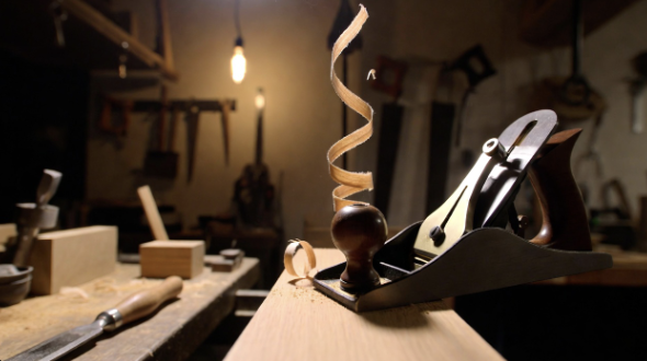 Hand plane taking thin wood shavings on a workbench