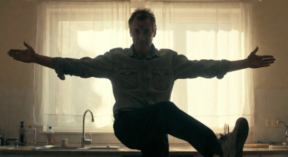 Man standing on one leg near a counter for balance