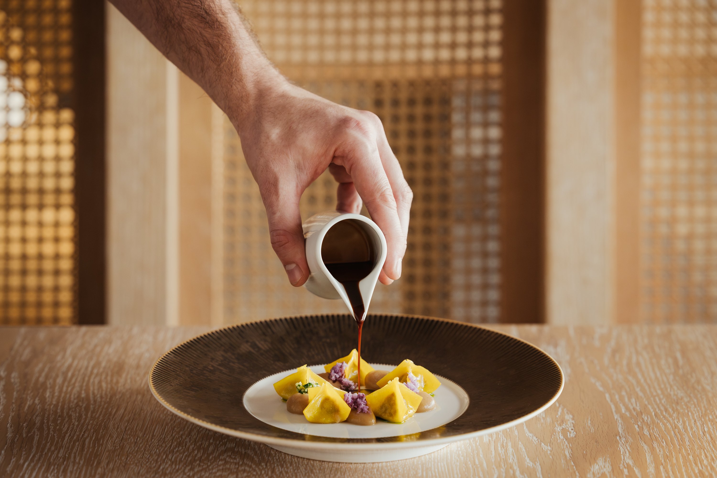 Sauce being poured onto a restaurant dish at Cape of Senses
