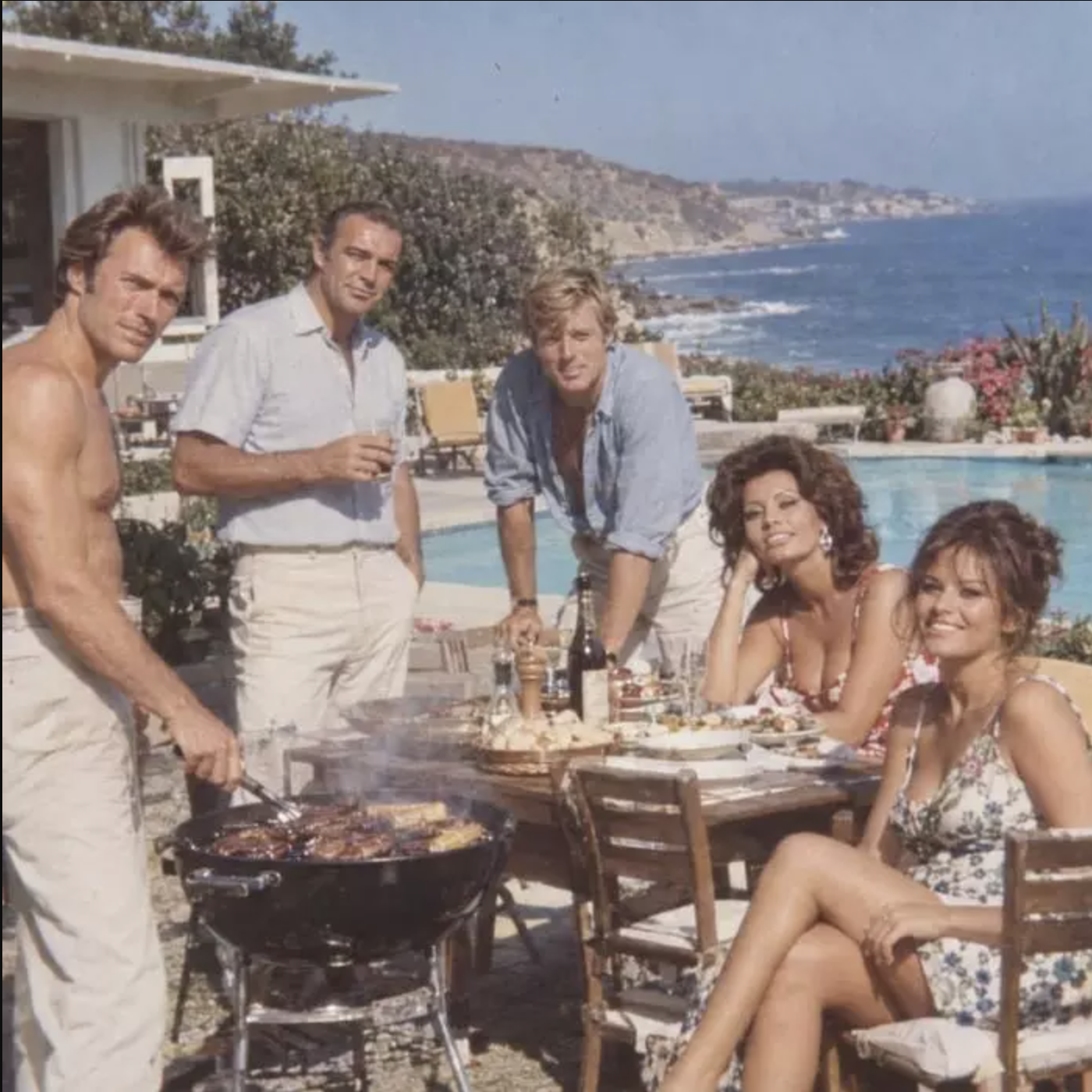 A sun-faded, vintage-style photo of five movie stars gathered around a backyard barbecue by the ocean, created with AI and passed off as a real 1965 snapshot