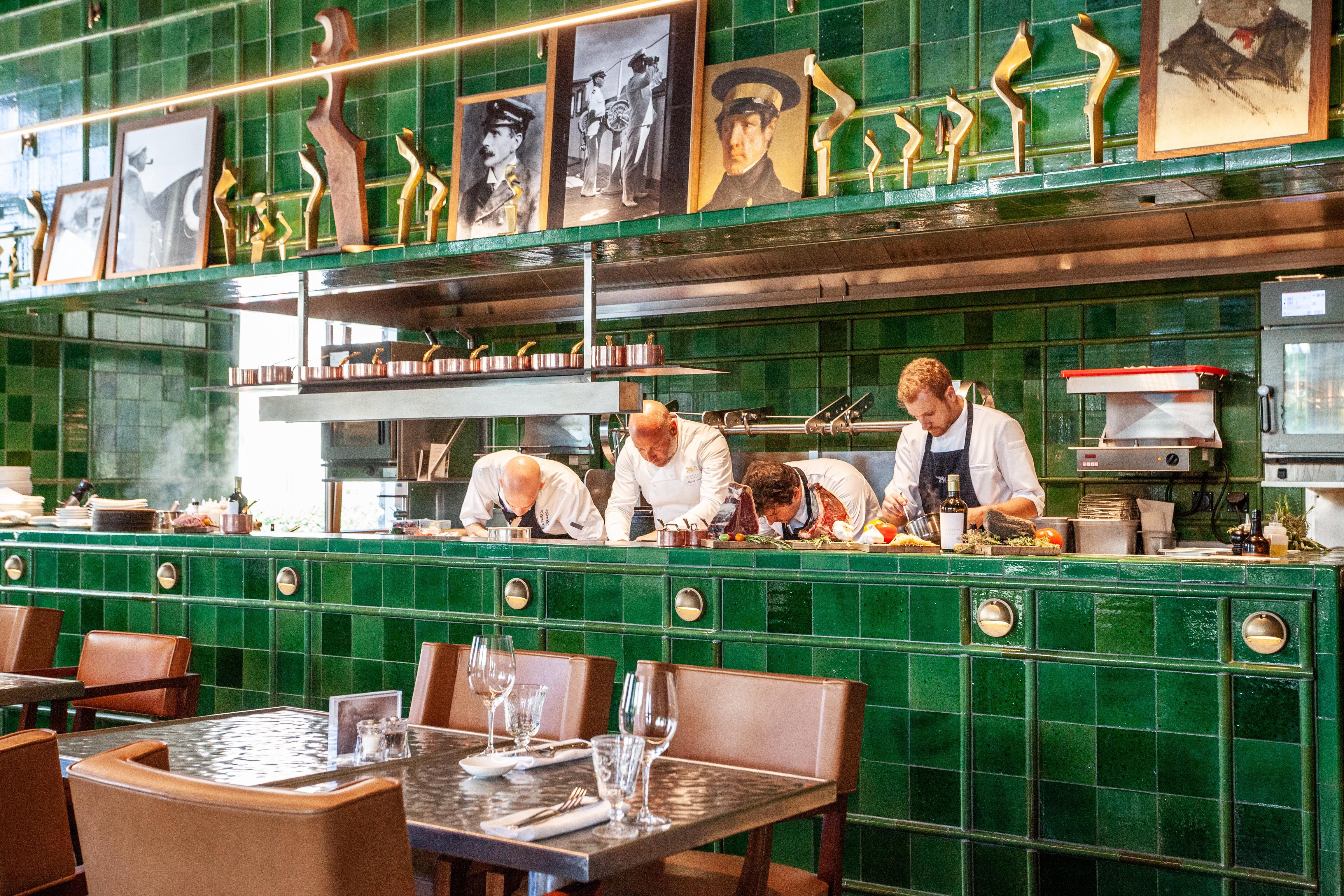 Open kitchen framed by green tiles at Eden Kitchen & Bar