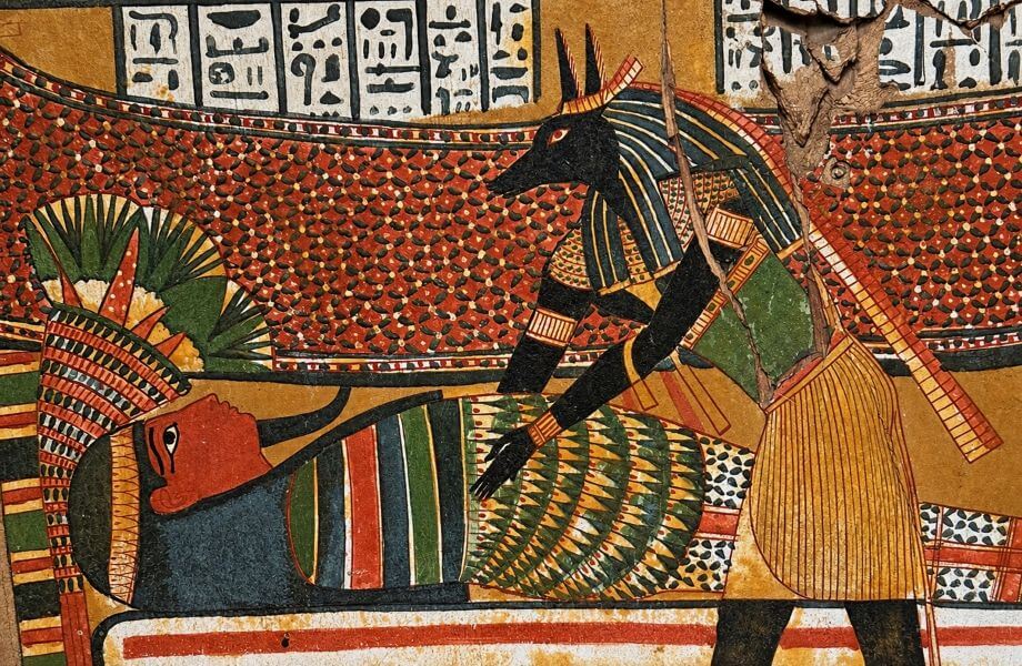 Ancient Egyptian funerary painting depicting Anubis, the jackal-headed god, attending to a mummified body.