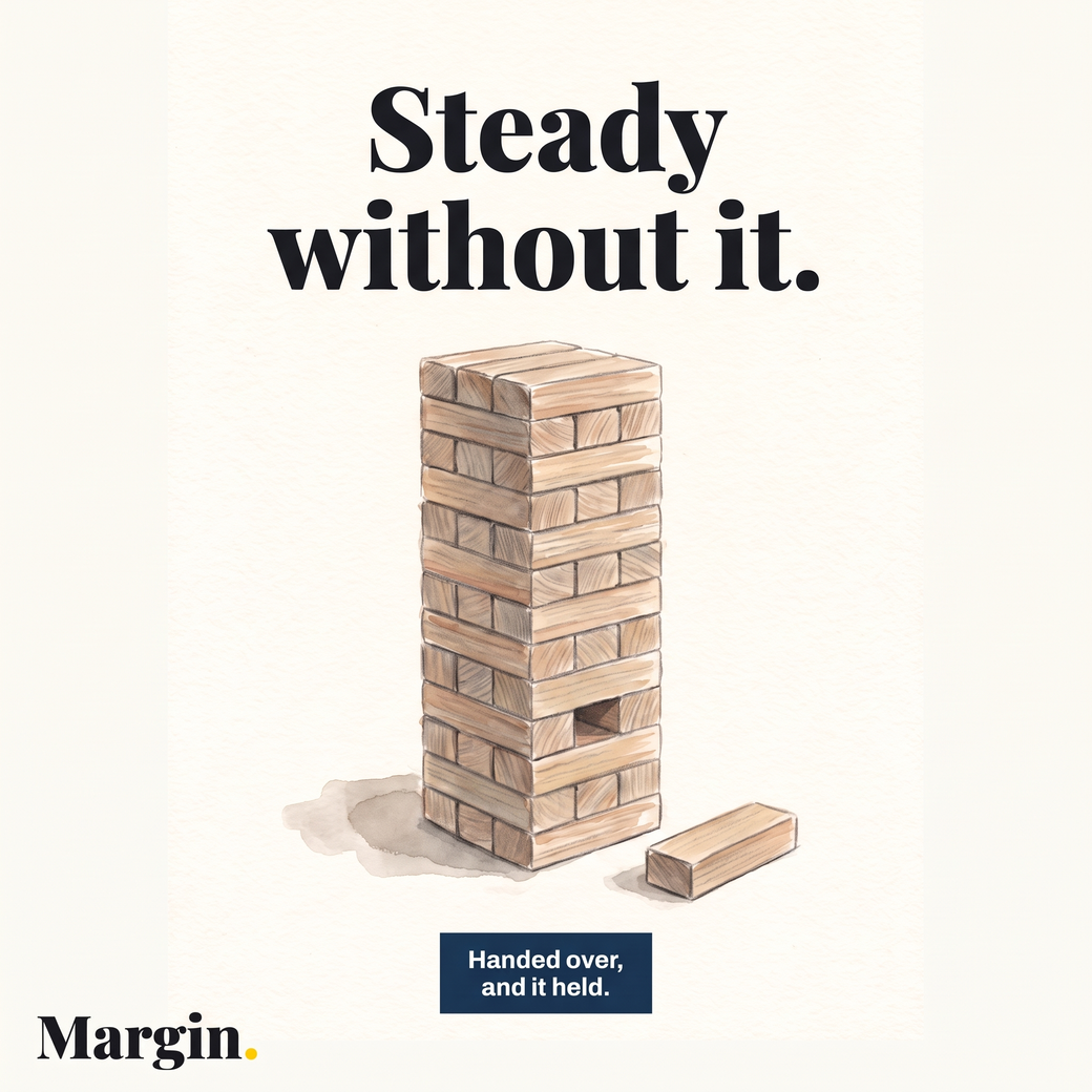 A Jenga tower standing straight with one block missing from the lower third of the stack. The removed block lies flat on the surface beside it. Nothing is leaning.