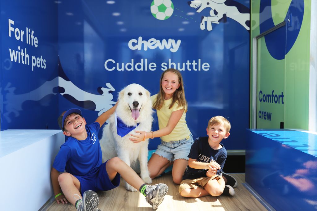 Children sit with a large white dog inside the Cuddle Shuttle during a Miami World Cup fan pop-up.