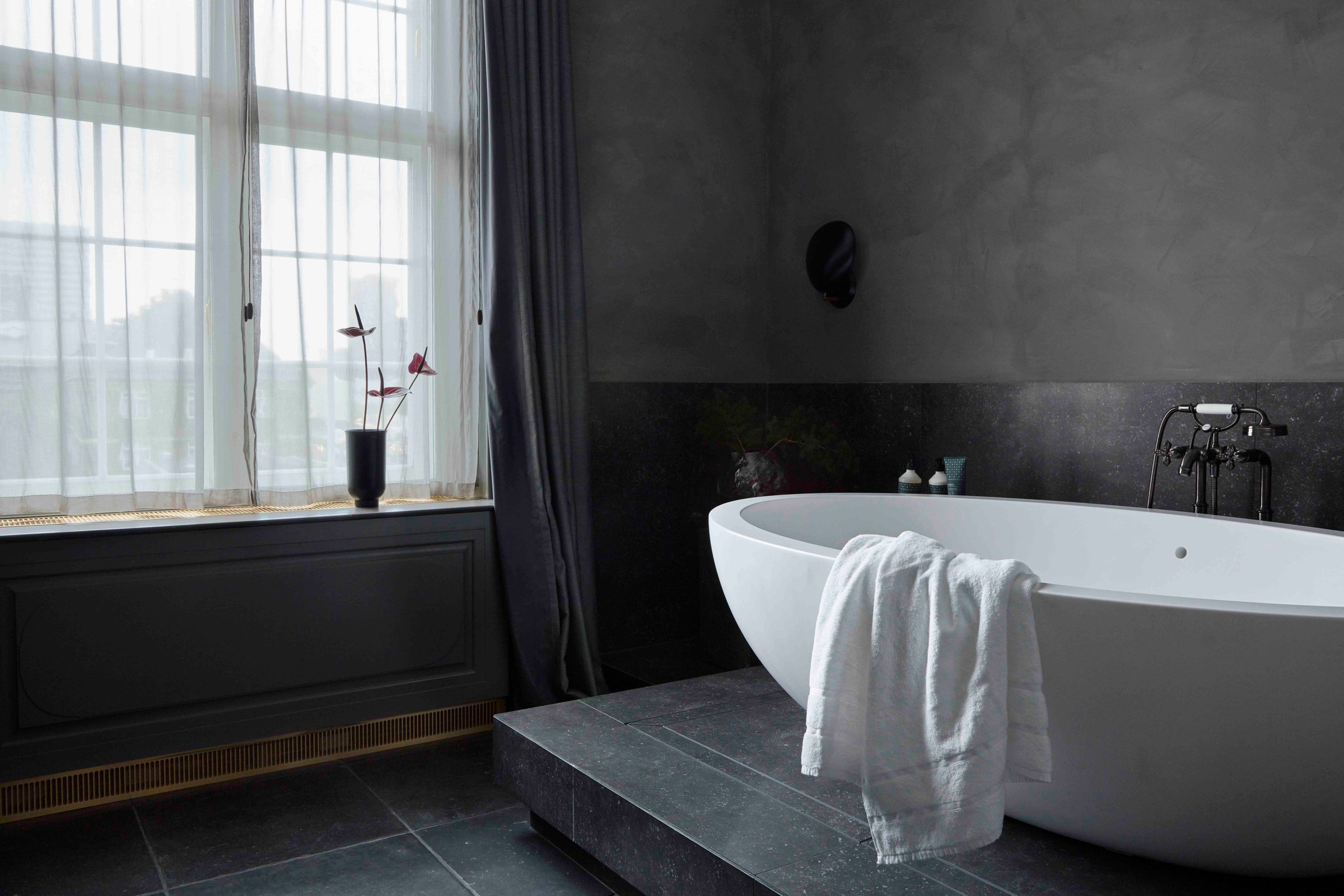 Dark tiled bathroom with a freestanding tub at Villa Copenhagen
