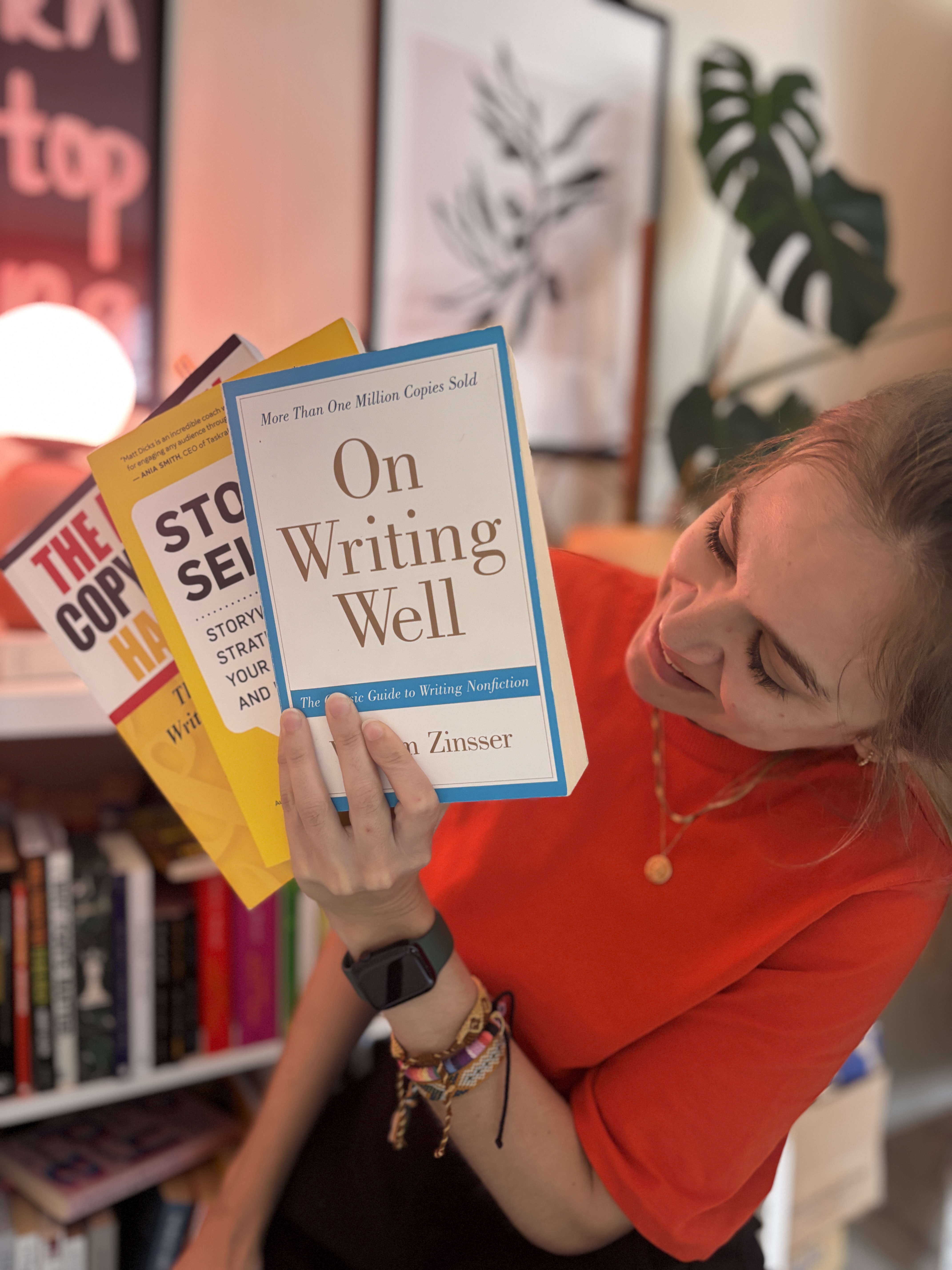 Laura Woythe in a red top, smiling at a fan of writing books including On Writing Well