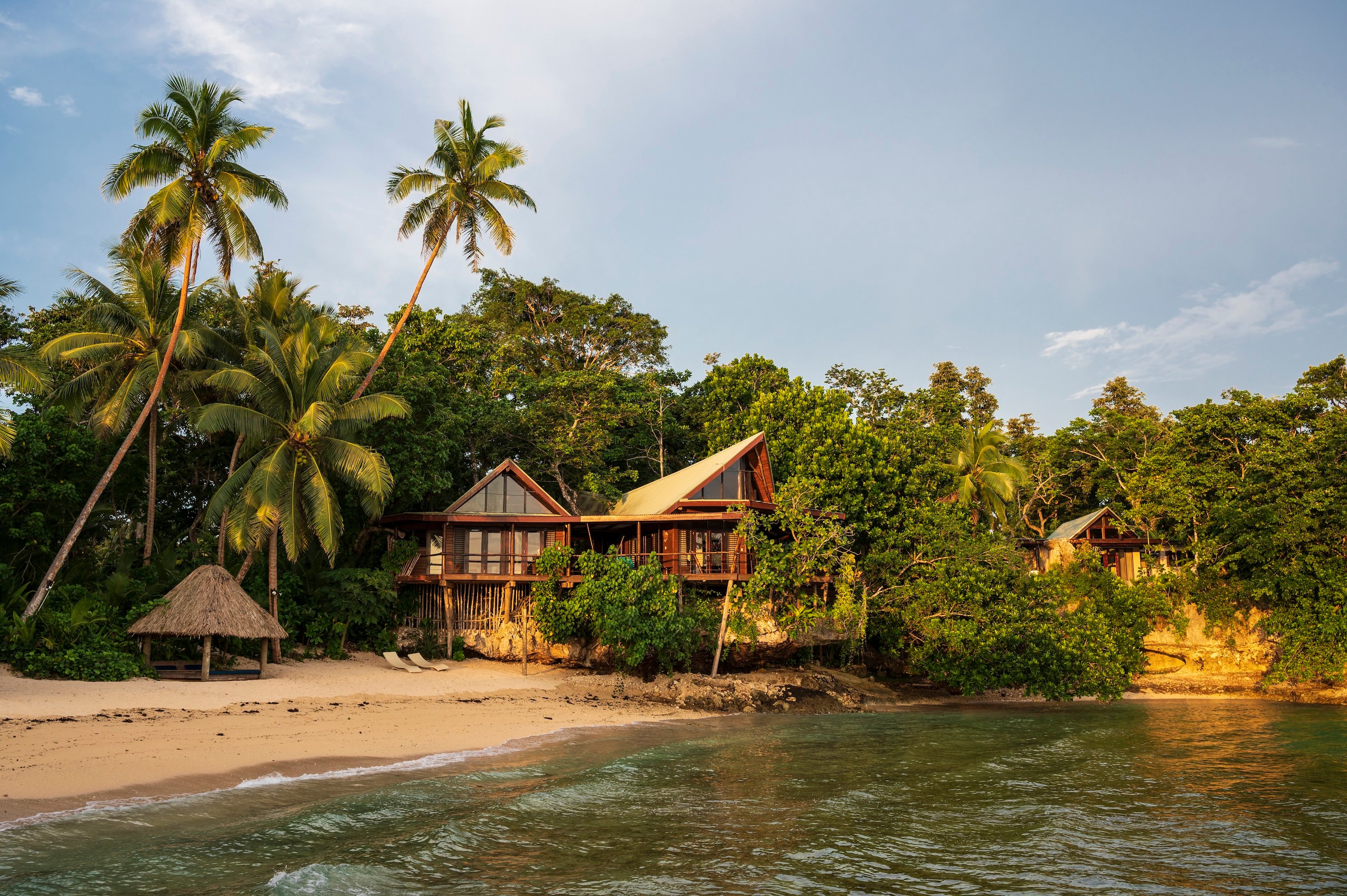 Beachfront wooden villas surrounded by palms at Savasi Island Resort
