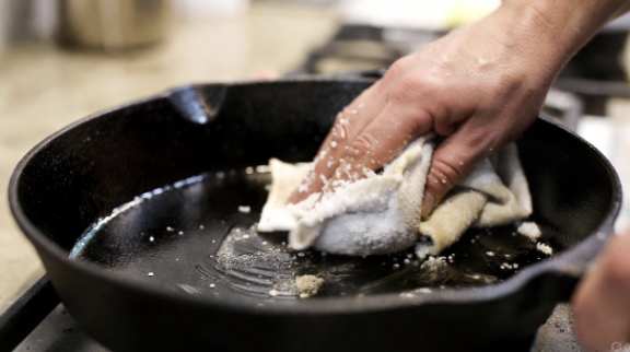 Cast iron skillet being cleaned with salt and a cloth