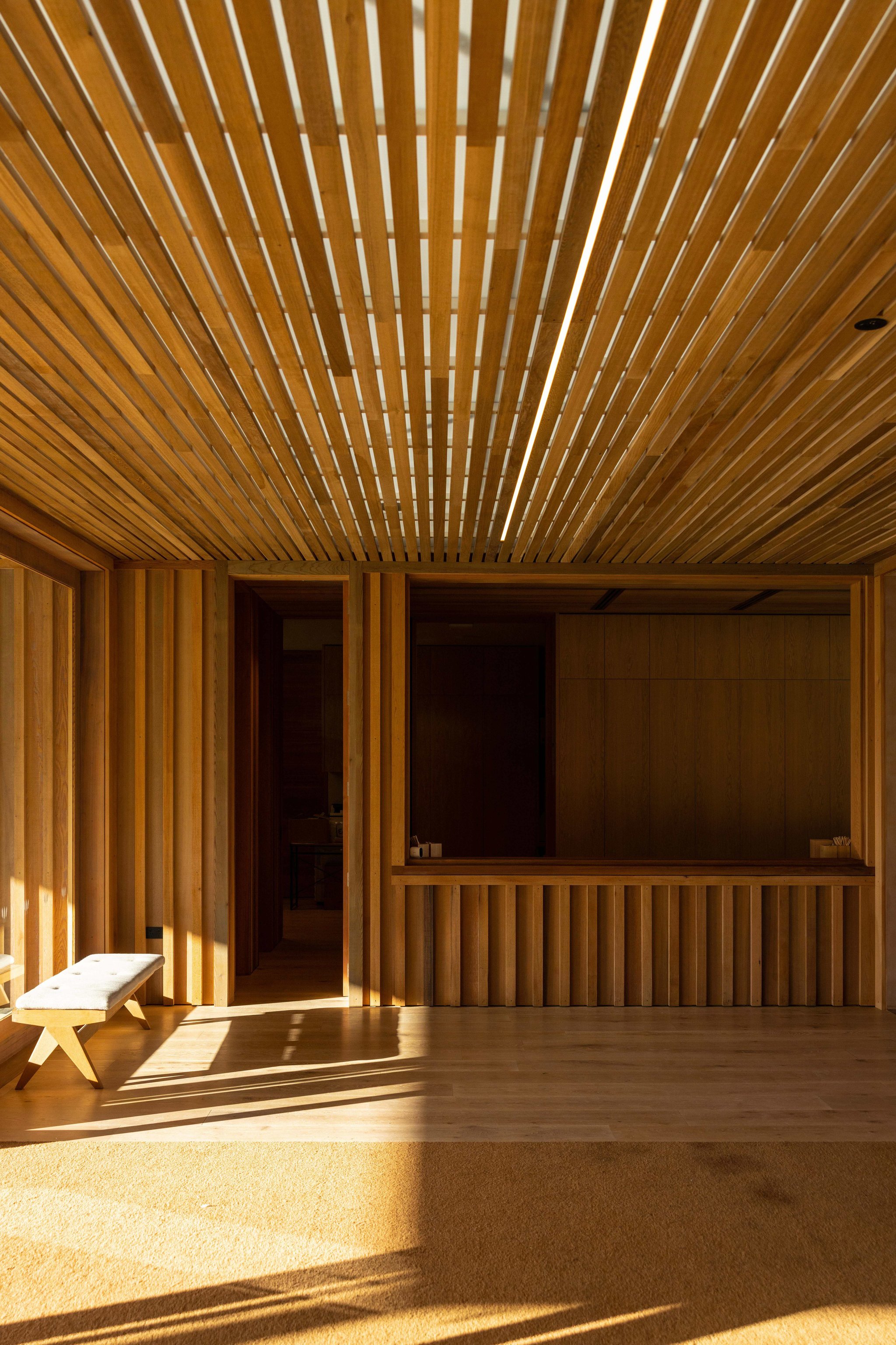 Sunlit timber-lined interior with slatted ceiling and wood furnishings
