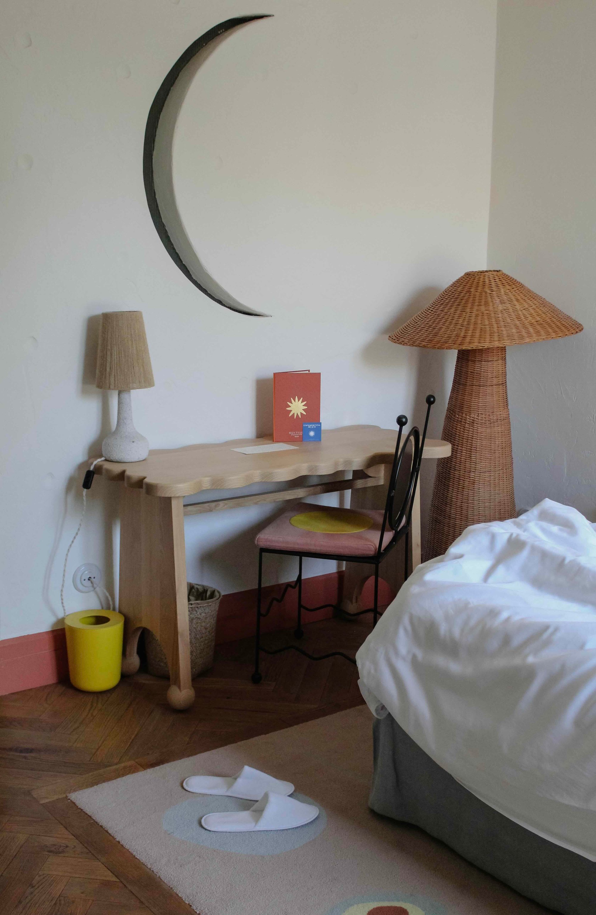 Guest room desk beneath a crescent-shaped mirror