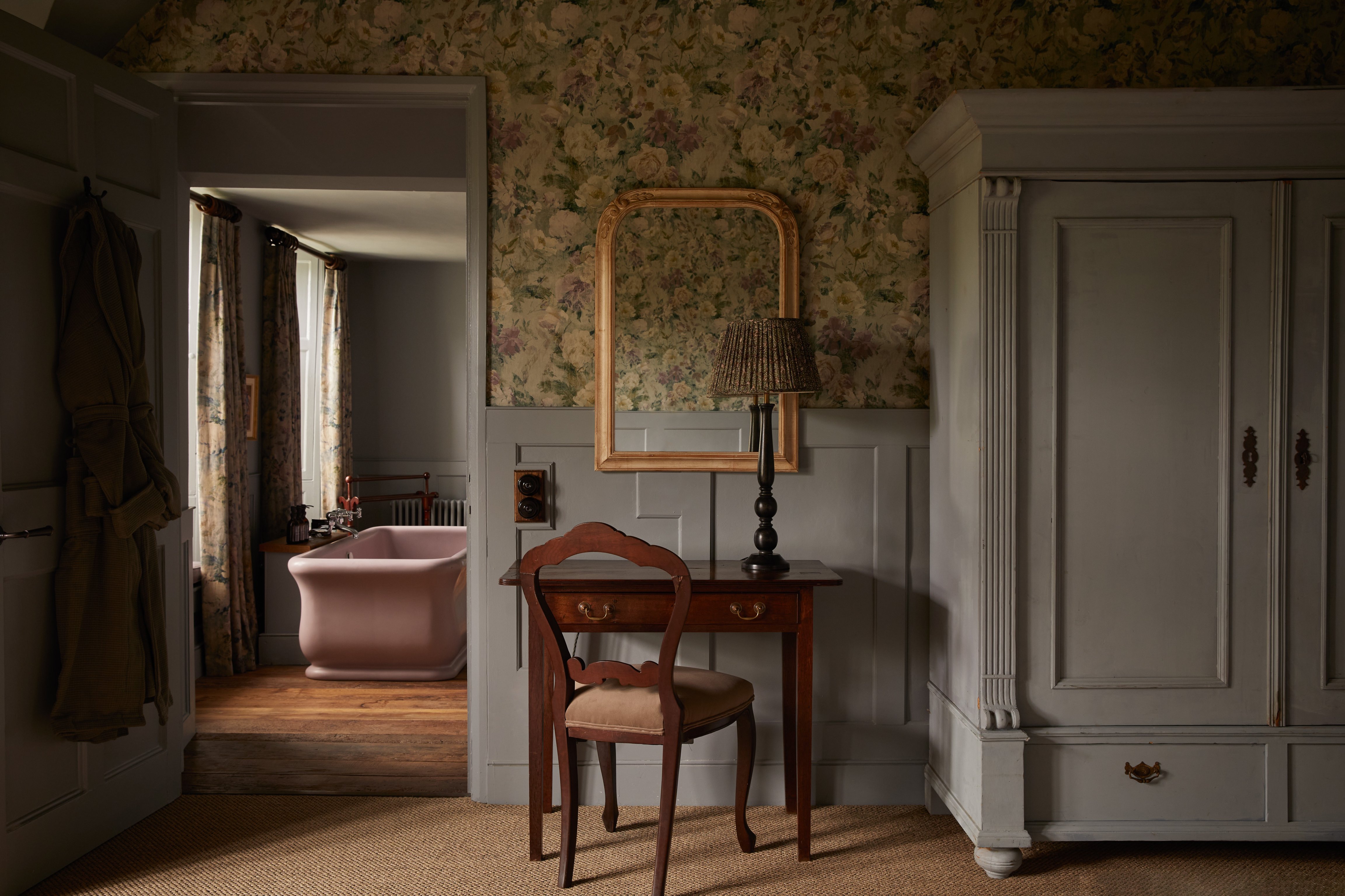 Floral wallpaper and a bathtub beyond a bedroom doorway at The Pig