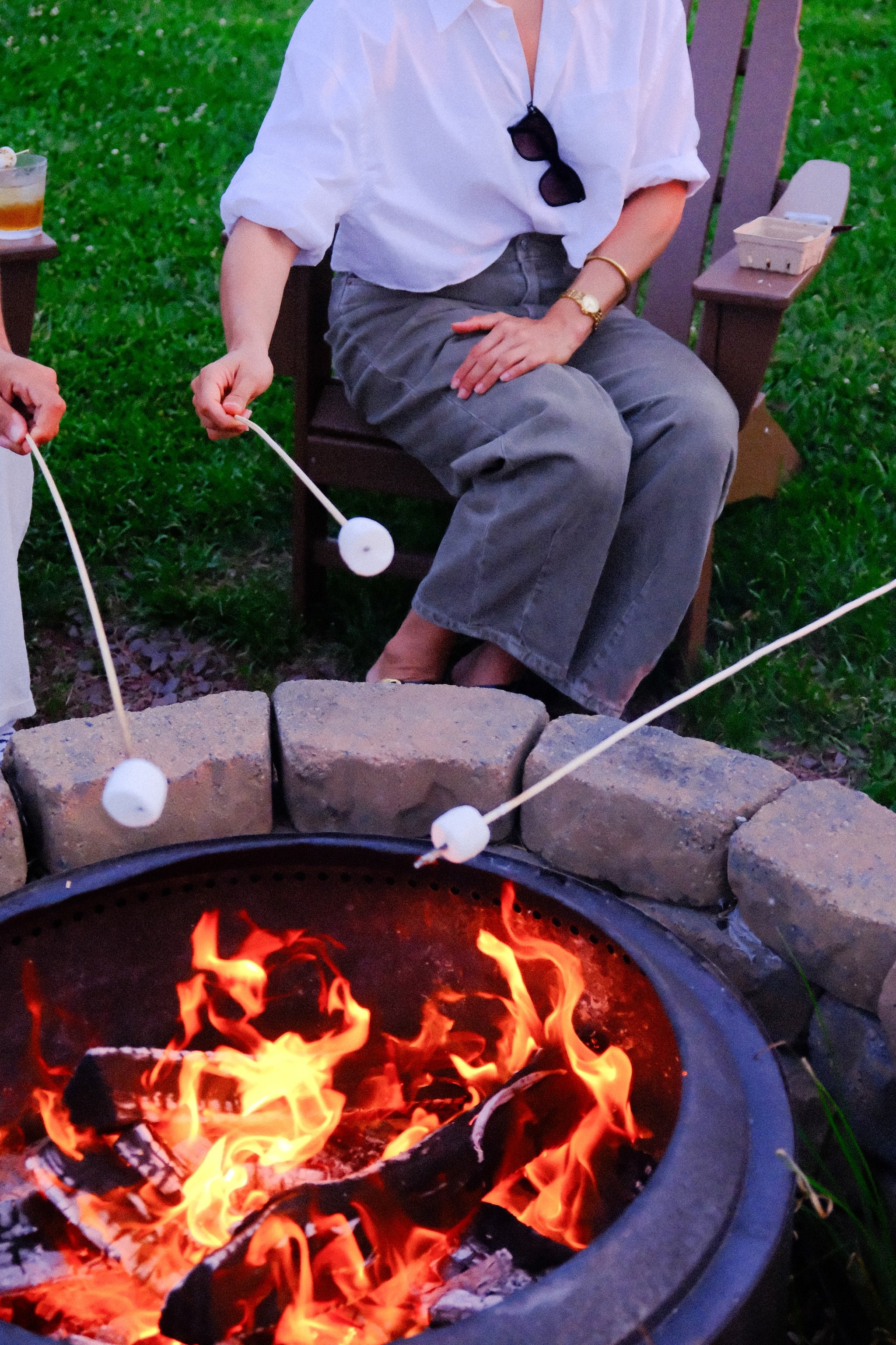 Guests roasting marshmallows around a fire pit on Governors Island